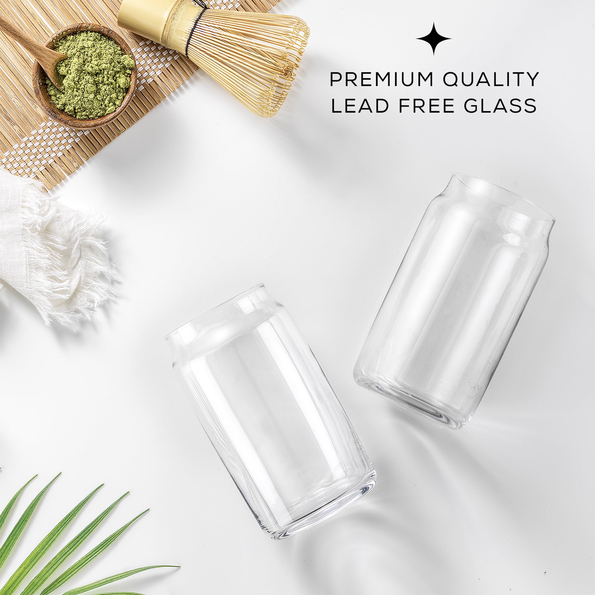 Two JoyJolt Classic Can Shape Tumbler Drinking Glass Cups sit on a white table next to a bowl of matcha powder and a whisk. The text on the image reads, "Premium Quality Lead Free Glass."