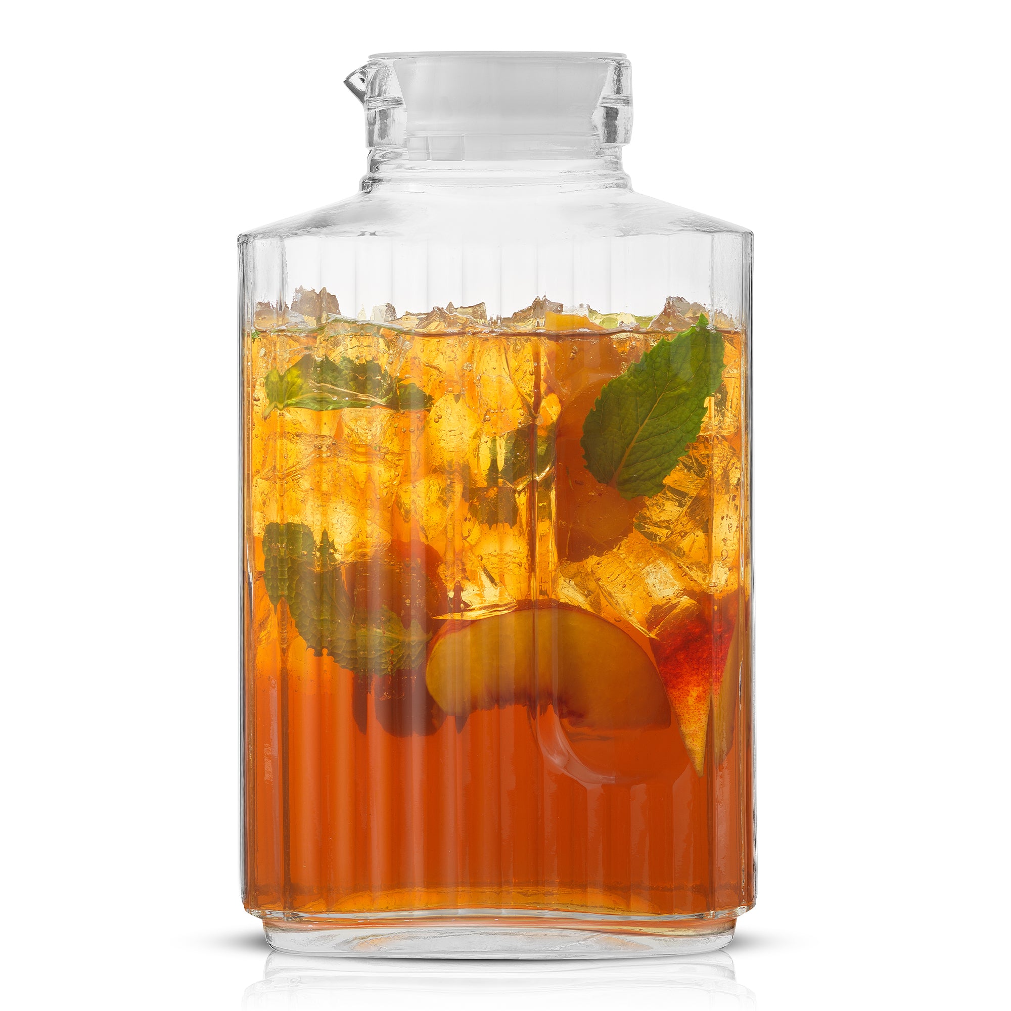 A clear JoyJolt Beverage Serveware Glass Pitcher filled with iced tea and mint leaves sits on a white background. The pitcher has a spout for pouring. Slices of peach in the tea with ice cubes.