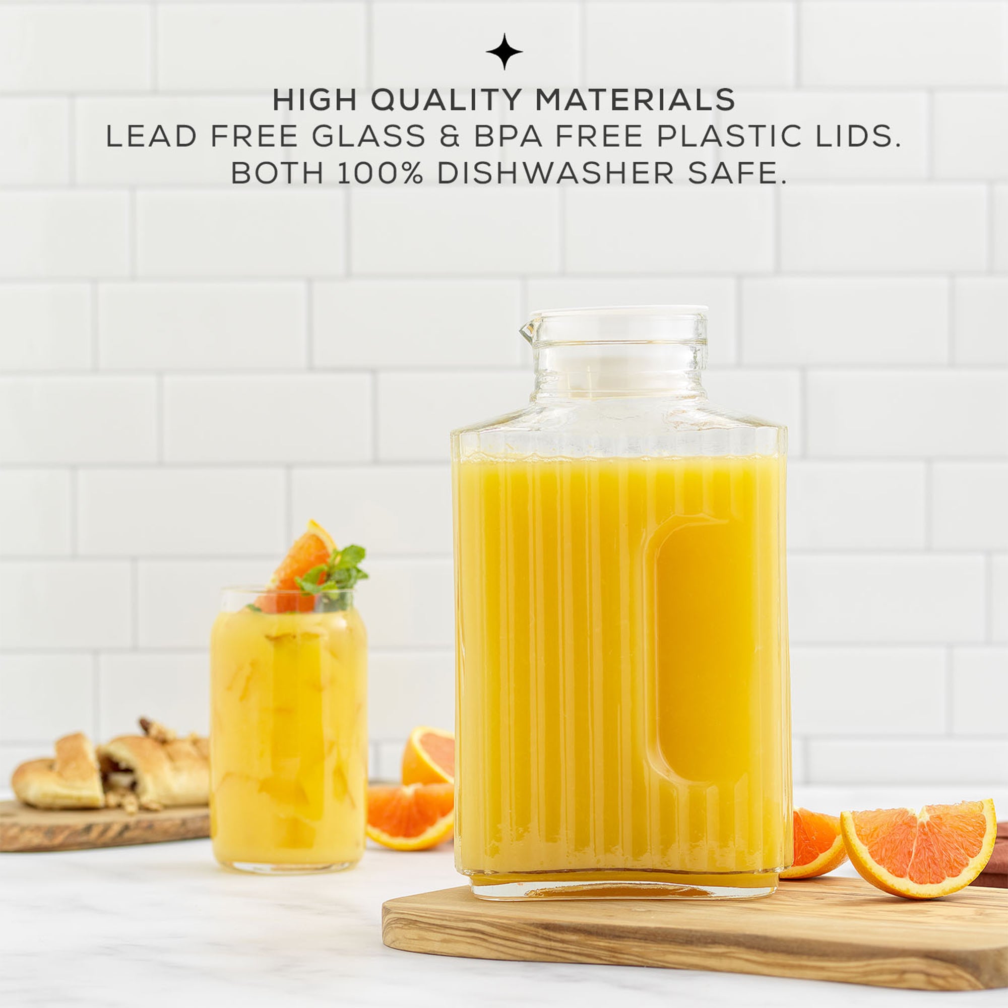 A JoyJolt Beverage Serveware Glass Pitcher filled with orange juice sits on a table. Text on the image reads: "HIGH QUALITY MATERIALS LEAD FREE GLASS & BPA FREE PLASTIC LIDS. BOTH 100% DISHWASHER SAFE."